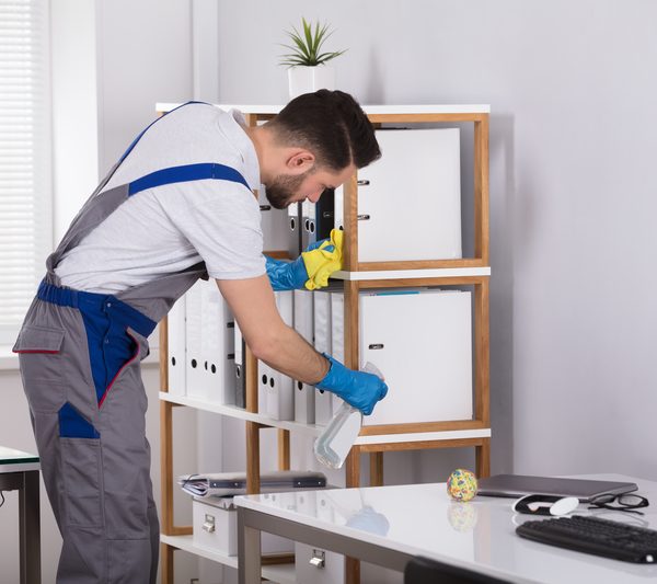 Man Cleaning Desk In Office